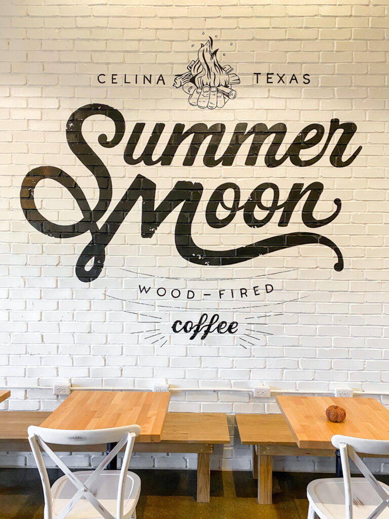 Interior shot of the Summer Moon logo in black on white painted brick, at the Celina, Texas location.