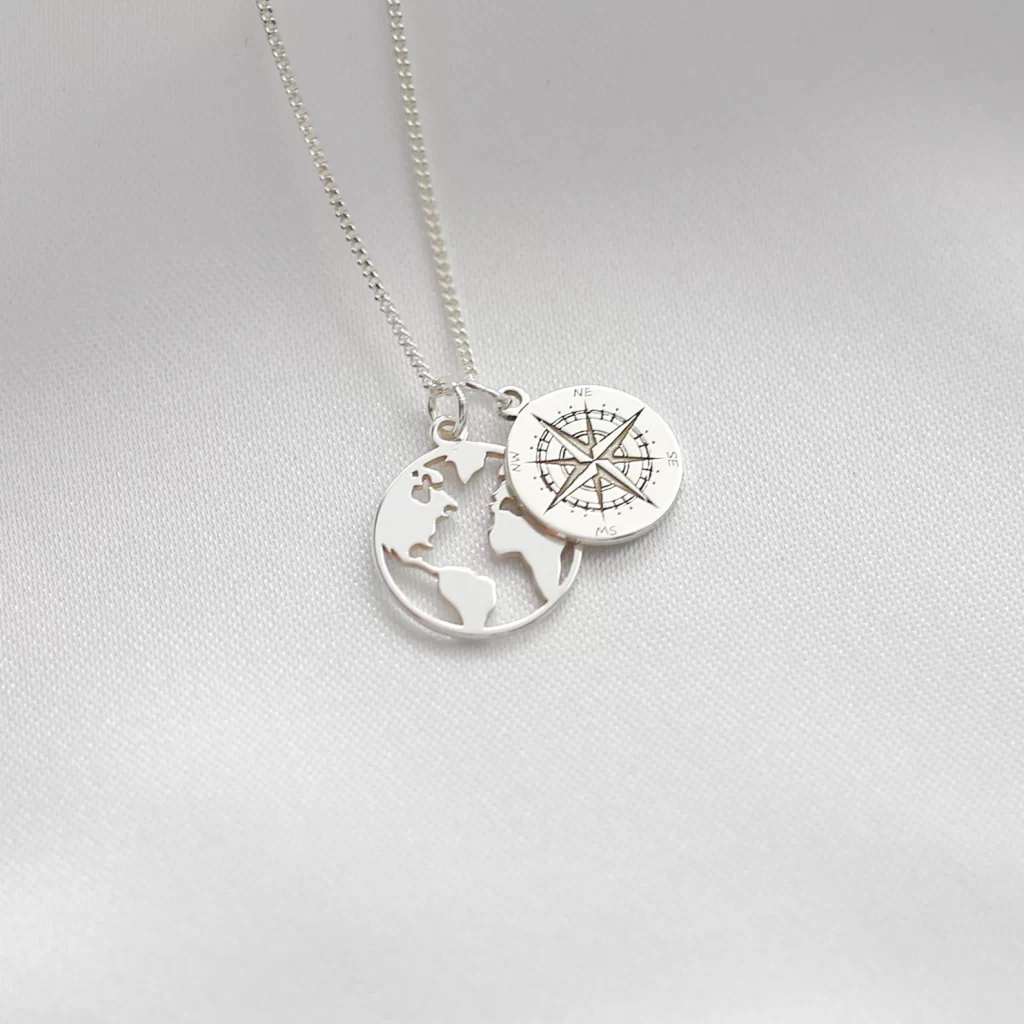 Silver pendant necklace on a silver chain with two pendants including a compass and a world map